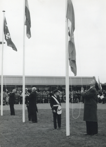 171111 Afbeelding van het hijsen van de vlaggen op het voorplein tijdens de opening van het nieuwe N.S.-station Beverwijk.